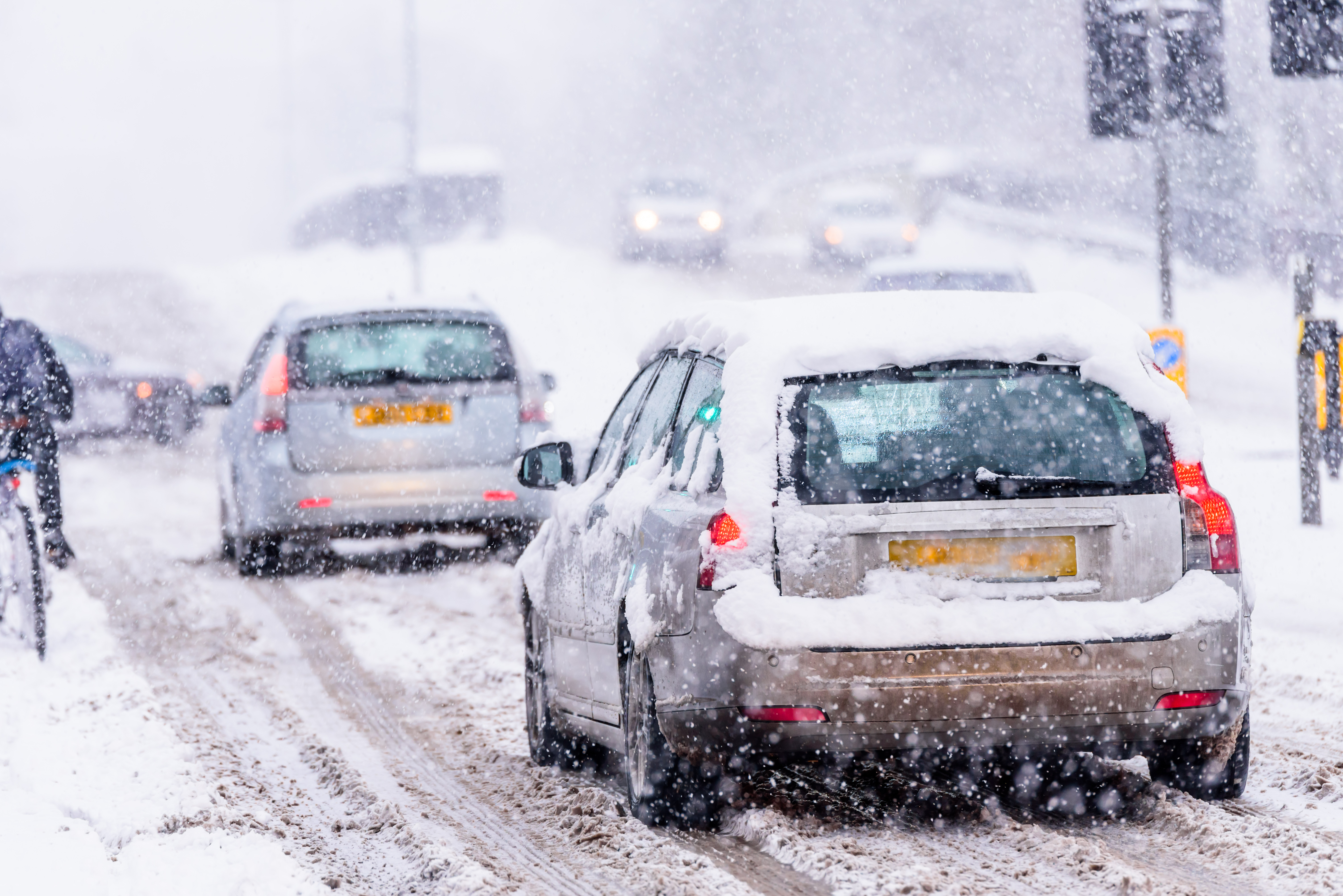 Car parked on a snowy UK road during winter with visible tyre tracks