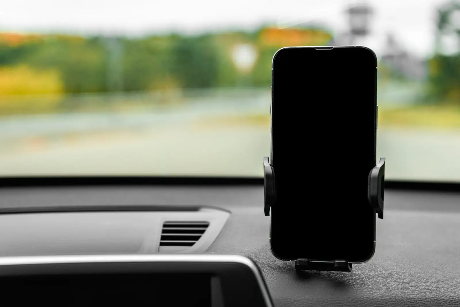 Car phone holder mounted on dashboard showing navigation for UK drivers